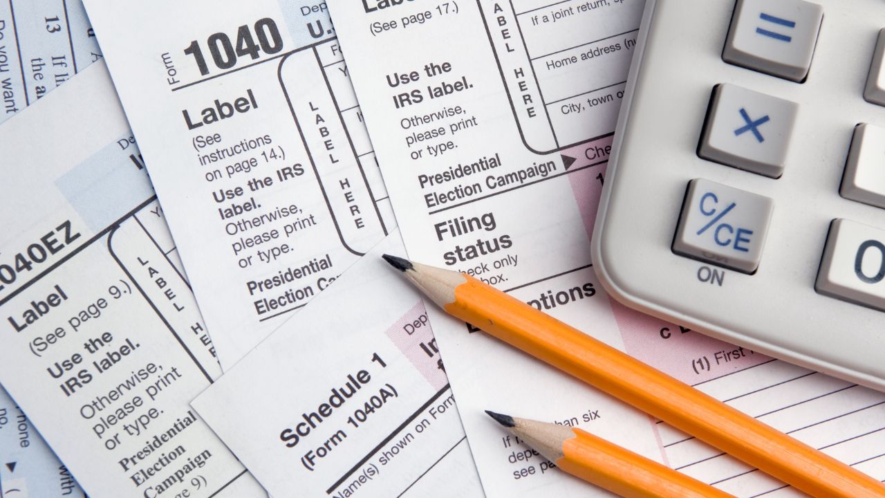 Dos lapices amarillos con calculadora encima de formularios 1040